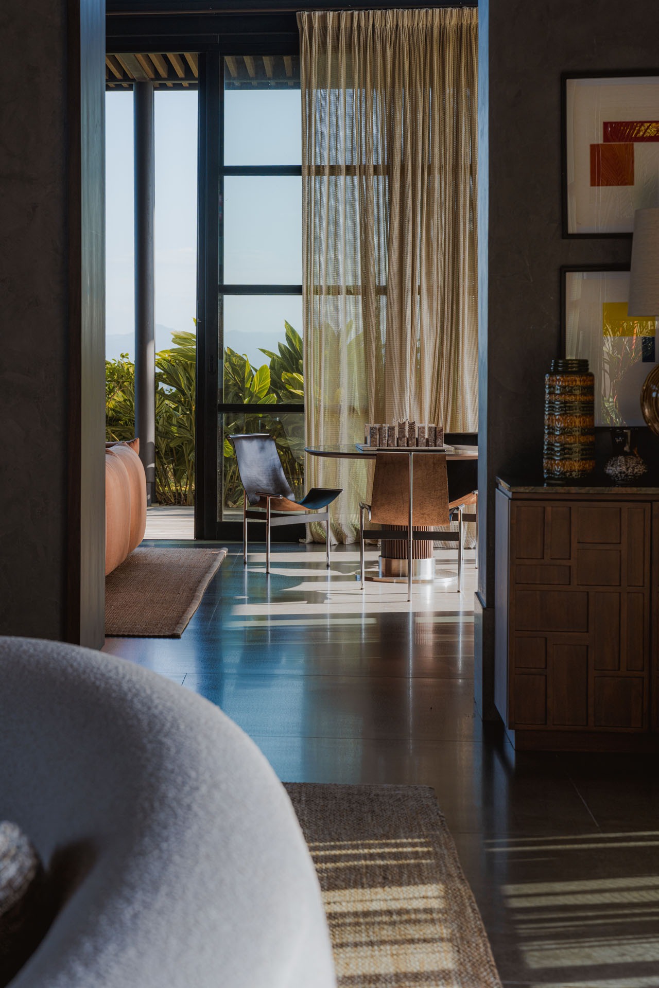 Interior living space looking out through open glass doors to tropical greenery at Dos Vistas in Cabuya, Costa Rica designed by Studio Saxe.
