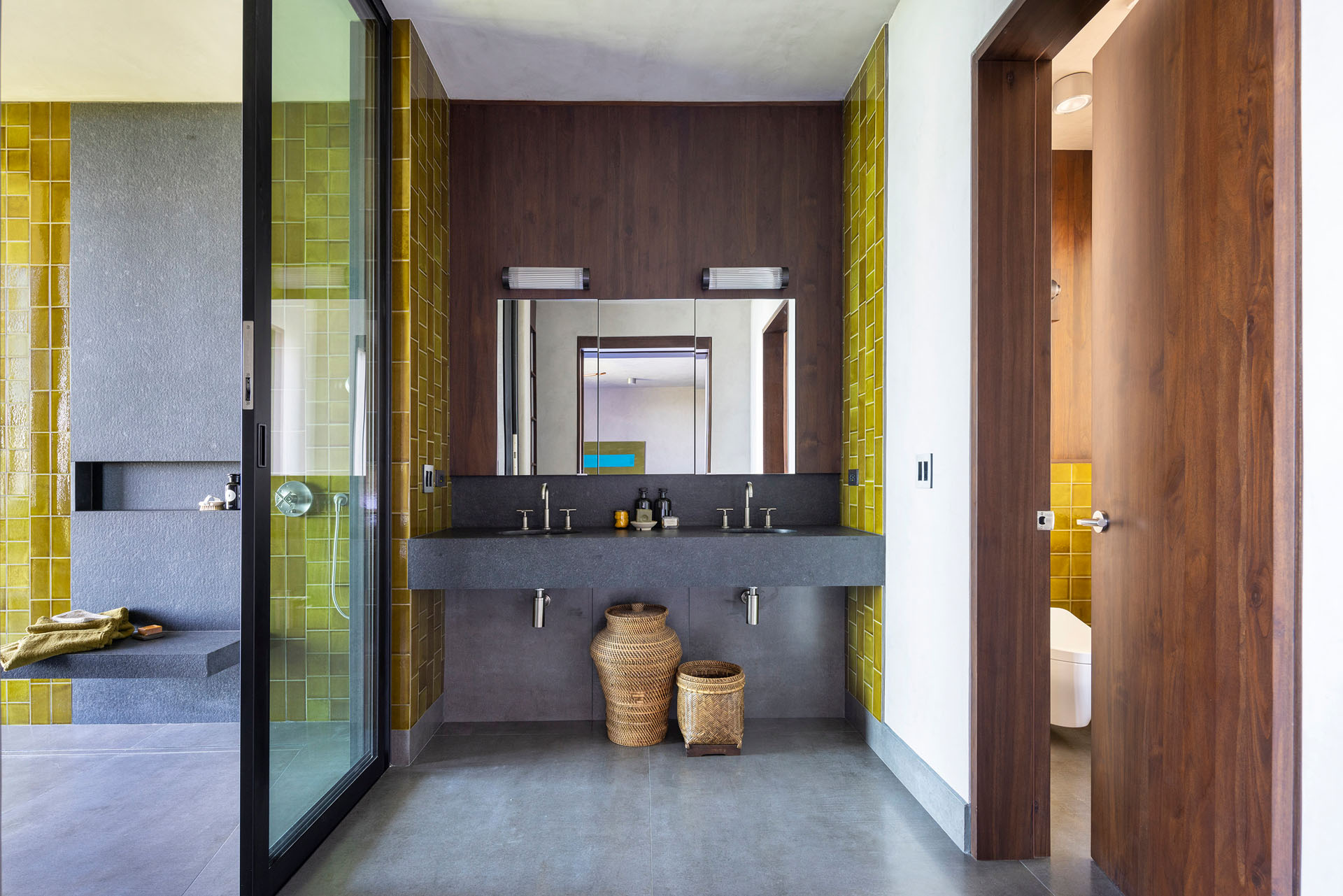 Interior bathroom featuring a floating stone vanity, custom wood paneling, and vibrant yellow accent tiles at Dos Vistas in Cabuya, Costa Rica designed by Studio Saxe.