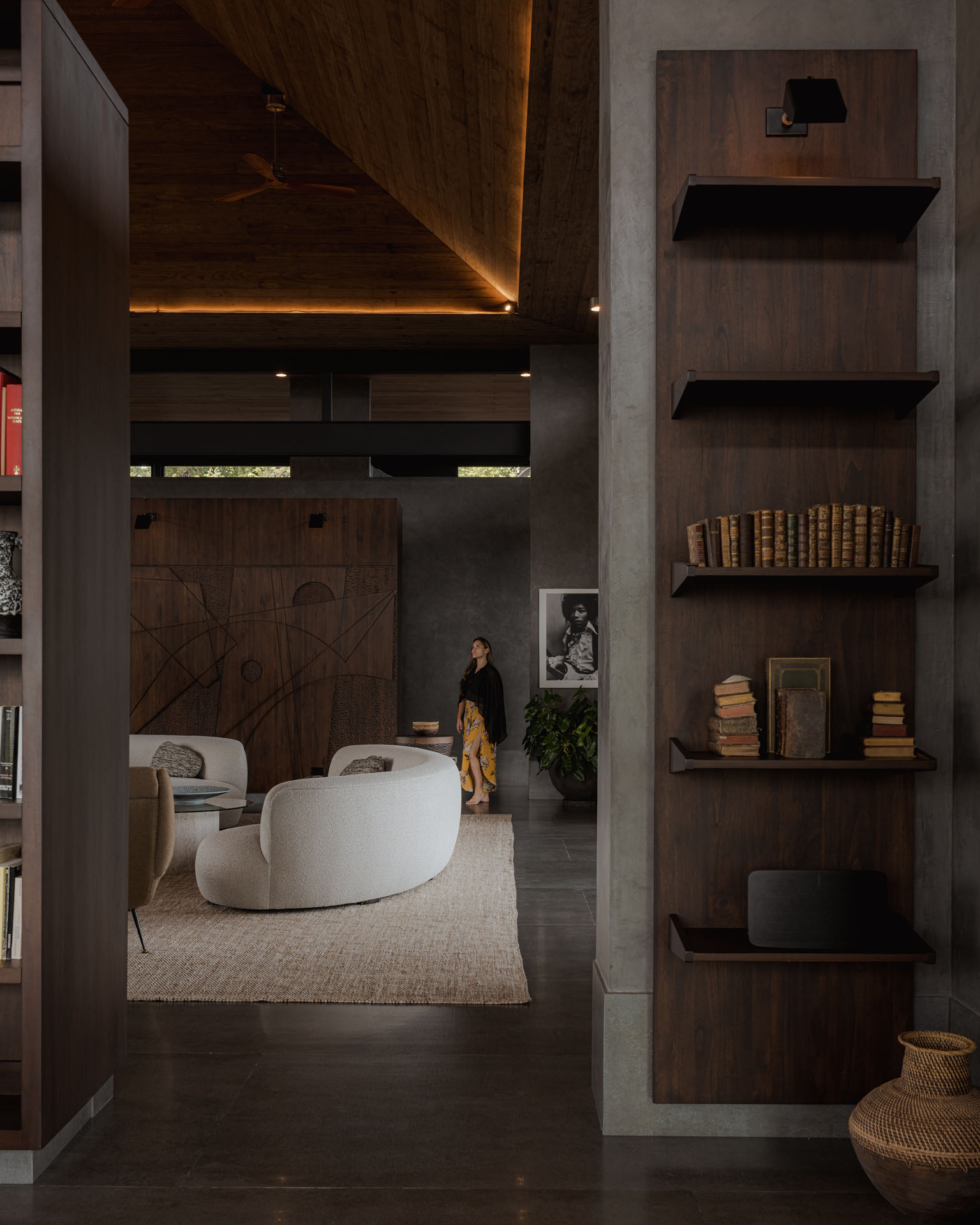 Interior architecture featuring custom dark wood shelving, concrete pillars, and an illuminated timber ceiling at Dos Vistas in Cabuya, Costa Rica by Studio Saxe.