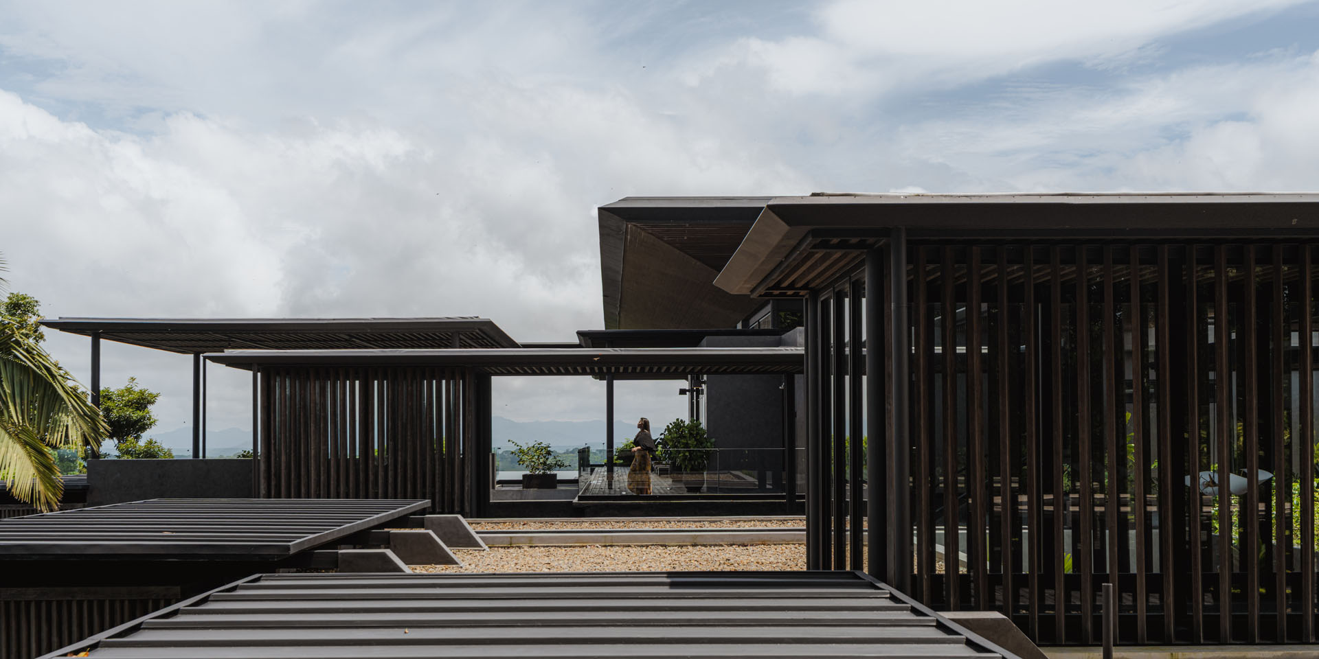 View across flat planted roofs and dark wooden slatted pergolas providing shade at Dos Vistas in Cabuya, Costa Rica designed by Studio Saxe.