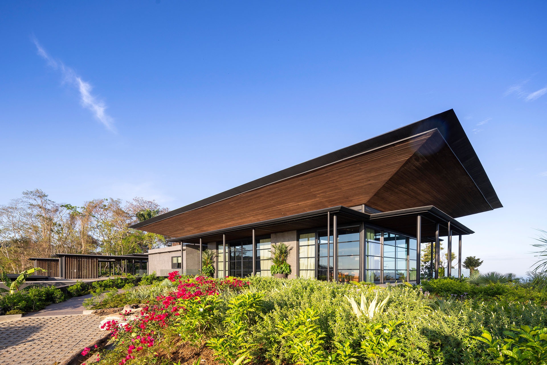 Exterior view of the lightweight, pagoda-like roof pavilion of the Dos Vistas residence surrounded by lush planted gardens in Cabuya, Costa Rica designed by Studio Saxe.