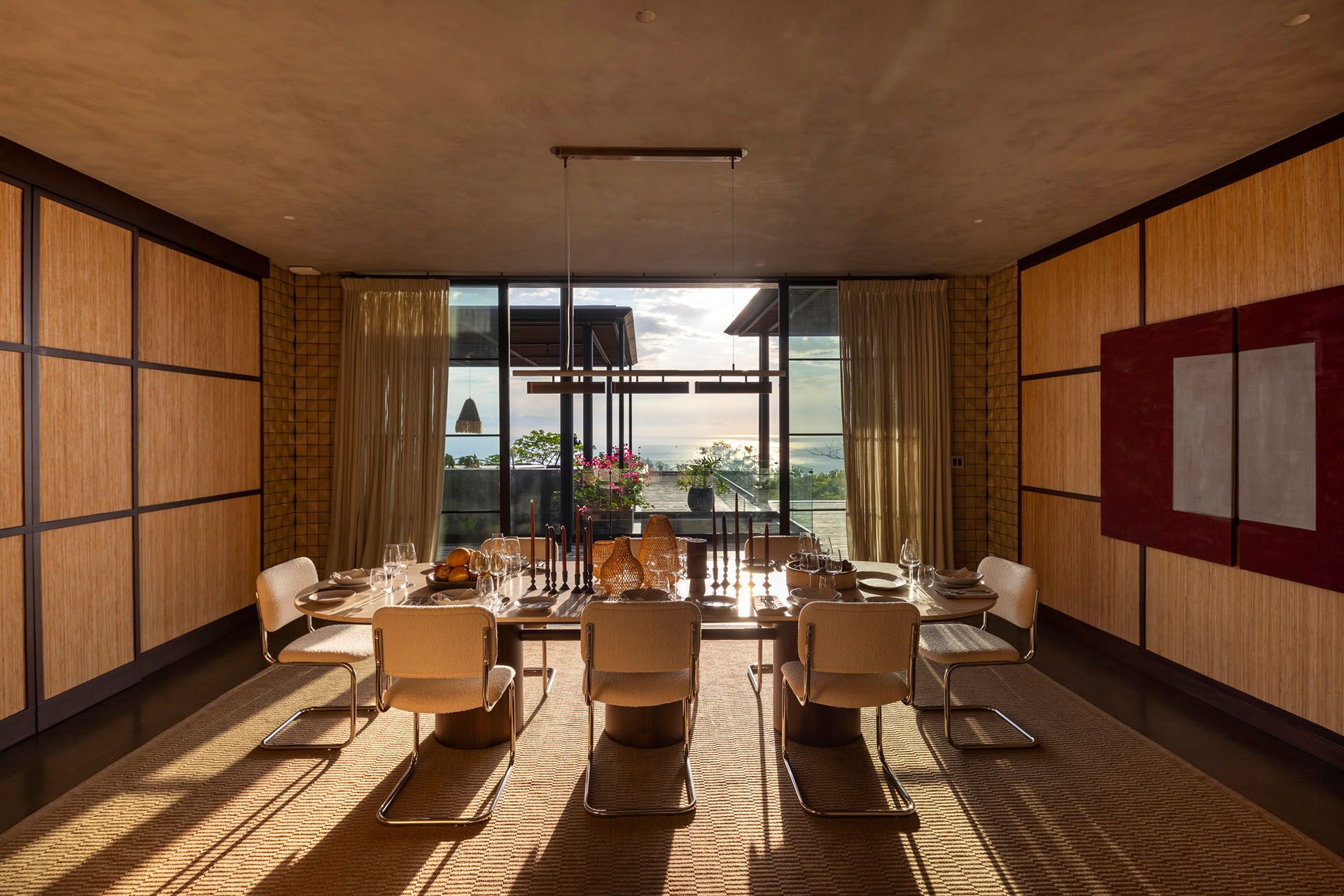 Interior dining room featuring woven wall paneling and a large table looking out to the ocean at Dos Vistas in Cabuya, Costa Rica by Studio Saxe.